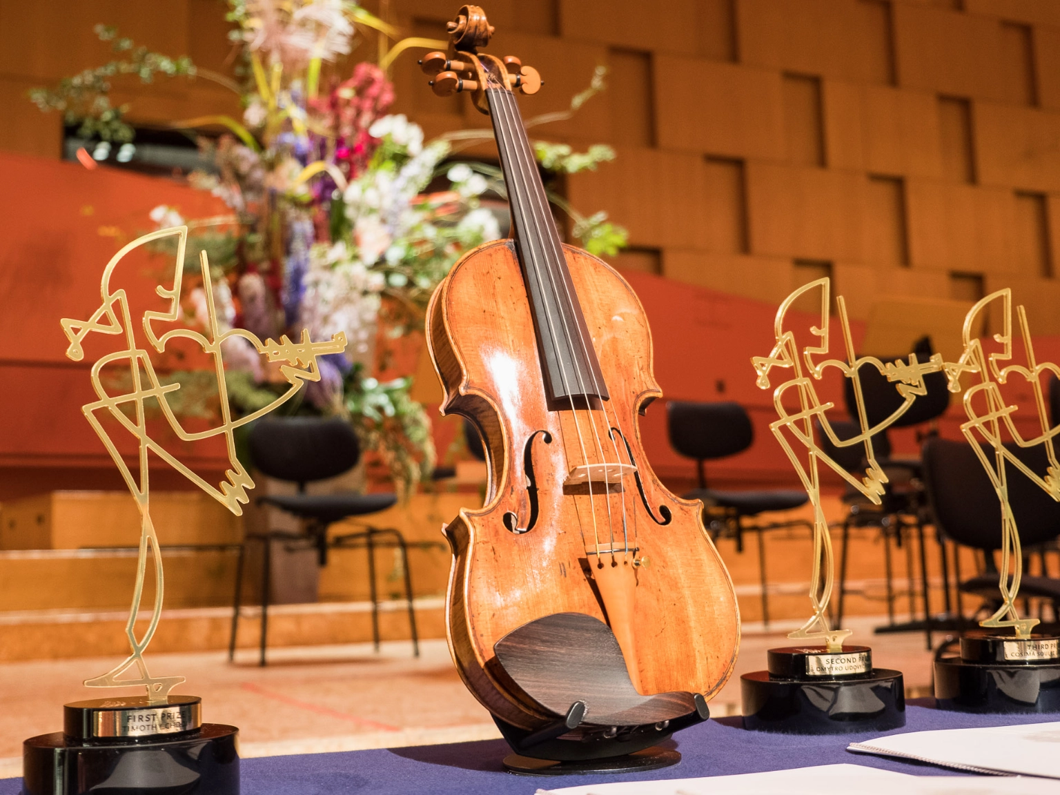 Seit dem Jahr 2000 verleiht die Fritz Behrens Stiftung aus Ihrem Besitz eine Giovanni Battista Guadagnini-Geige (Parma ca. 1765) an eine*n Teilnehmer*in des Internationalen Joseph Joachim Violinwettbewerbs Hannover. Im Hintergrund die goldene Preisstatuetten des Violinwettbewerbs, gestaltet von Sebastian Peetz.