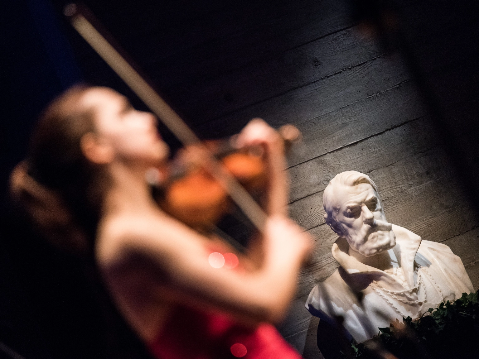 Die Porträtbüste von Joseph Joachim in der Hochschule für Musik, Theater und Medien Hannover. Die Büste im Hintergrund ist scharf zu erkennen, im Vordergrund unscharf eine junge Geigerin im roten Kleid